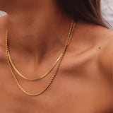 Elegant double layered gold necklace featuring minimalist and delicate design, worn around the neck and chest as a fashionable metal jewelry accessory.