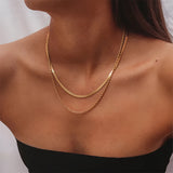 Elegant double layered gold necklace displayed on a model's neck, showcasing minimalist and delicate design.