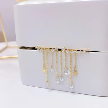 Elegant gold chain drop earrings with crystal star charms displayed on a beige rectangular background, showcasing detailed metalwork and sparkling crystals, perfect for women's fashion.