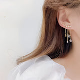 Elegant gold chain drop earrings with crystal star charms worn by a woman, highlighting facial features and shoulder.