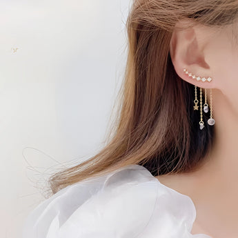 Elegant gold chain drop earrings with crystal star charms worn by a woman, highlighting facial features and shoulder.