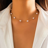 Elegant gold chain pearl necklace worn around the neck of a model dressed in beige outerwear, highlighting the necklace as a perfect bridal gift or accessory for her.