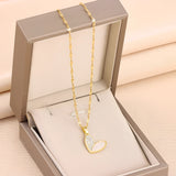 Elegant gold chain necklace featuring a white enamel heart pendant adorned with rhinestones, displayed on a wooden surface.