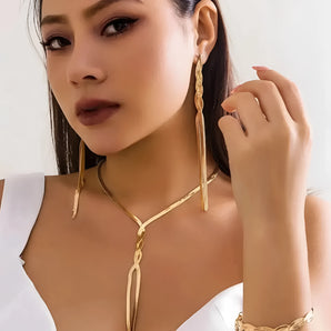 Close-up of a woman wearing elegant gold earrings, a body chain necklace, and a luxury bracelet set.