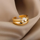 A woman's hand wearing an elegant gold floral engagement ring with a unique diamond twist band, paired with a dress.