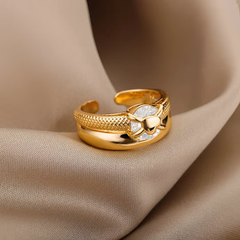 A woman's hand wearing an elegant gold floral engagement ring with a unique diamond twist band, paired with a dress.
