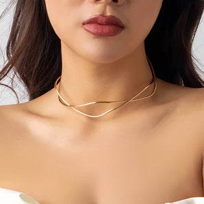 Close-up of a woman wearing a gold layered choker featuring a double band design, highlighting her neckline and complementing her minimalist style.