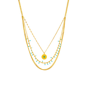 Elegant gold layered necklace featuring a sunburst pendant and turquoise beads, showcasing intricate design with symmetrical elements and fashion-forward appeal.