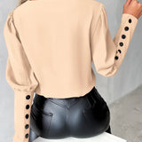 
A woman wearing an elegant light pink blouse with buttoned sleeves, showcasing the upper body and shoulders.