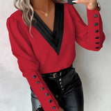 A woman wearing a red long-sleeve blouse with button details, featuring a collar and tailored fit, suitable for an elegant look.