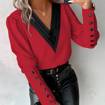 A woman wearing a red long-sleeve blouse with button details, featuring a collar and tailored fit, suitable for an elegant look.