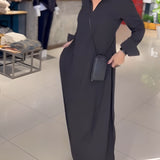 Elegant long black maxi dress with high collar, sleeves, and pockets, designed for formal wear and fashion events.