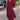 Elegant long black maxi dress with a high collar and pockets, showcasing a sophisticated one-piece garment design. The dress is displayed in a setting that includes houseplants and flowerpots, emphasizing a fashion-forward style suitable for formal events. The dress features long sleeves and a defined waistline, contributing to its elegant appearance.