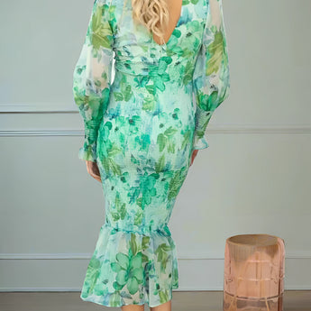 Elegant pink floral maxi dress with long sleeves worn by a model, showcasing a flowing silhouette suitable for an autumn evening. The dress features intricate floral patterns, complemented by the model's soft curls and delicate pose with visible arms and legs.