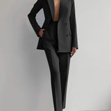 Elegant pink women's suit featuring a tailored blazer with sleeves and matching trousers, showcased on a model with emphasis on shoulder, waist, and leg fit, complete with sunglasses accessory.