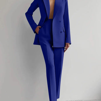 
A woman modeling an elegant blue tailored blazer and trouser set, featuring a structured shoulder and classic collar, suitable for formal or business occasions. The ensemble is designed with attention to detail, emphasizing the waist for a flattering fit.