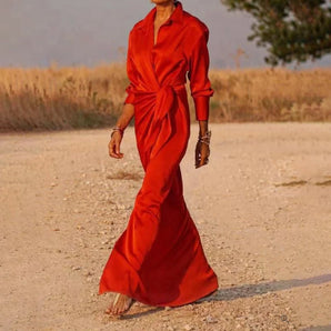 Elegant red satin wrap maxi dress displayed on a mannequin, showcasing its luxurious fabric and formal design. The dress features a deep neckline, long sleeves, and an elegantly cinched waist, embodying a sophisticated evening gown style.