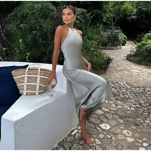 Elegant satin halter slip dress in a neutral shade, featuring a flowing maxi design perfect for summer events, with focus on the shoulders and waist.