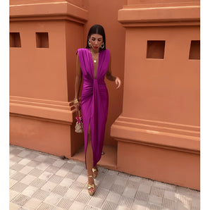 Elegant sleeveless purple gown featuring a draped neck and high slit, displayed in front of a window, highlighting its sophisticated design and vibrant violet hue.