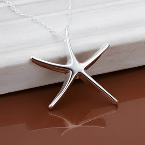 Elegant sterling silver starfish pendant on a wooden background showcasing its nautical beach jewelry design.