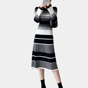
A navy and grey striped knit long sleeve sweater dress is displayed, featuring a one-piece garment design. The dress is modeled on a human body, highlighting its outerwear style with visible shoulders and neck.