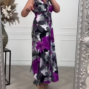 Elegant V-neck tie-waist floral maxi dress in black and purple, featuring short sleeves and a flowing silhouette with floral patterns.