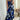 Elegant V-neck floral maxi dress with a tie-waist design in a blend of black and purple hues, featuring long sleeves and a flowing silhouette that accentuates the waist.