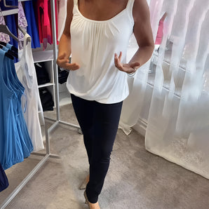 Elegant white draped blouse with a loose fit design, featuring a sleeveless cut suitable for summer wear.