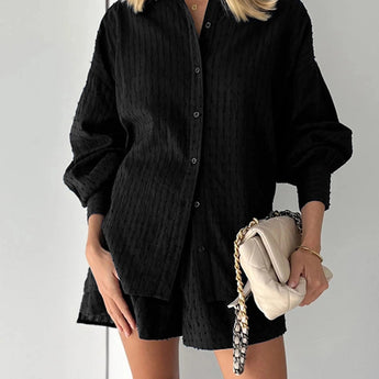 Elegant white lace blouse with sheer panels and intricate embroidery, modeled by a person also wearing black shorts.