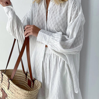 Elegant white lace blouse with sheer panels and intricate embroidery, featuring long sleeves and a structured collar.