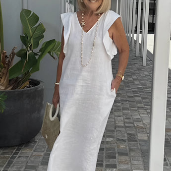 Elegant white linen V-neck summer dress on display, complemented with a pearl necklace.