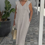 A stylish gray V-neck summer dress in a 3XL size, accessorized with a pearl necklace, featuring a model with sunglasses and shoulder-length hair, posed outdoors.