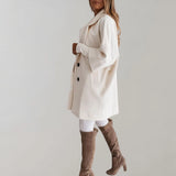 Elegant women's beige oversized wool coat featuring a high-collar design, long sleeves, and a tailored waist, showcasing a stylish winter fashion aesthetic.