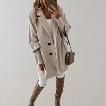 Elegant women's oversized wool coat in light gray, featuring a high collar and long sleeves. The coat is designed to provide warmth and style, reaching down to the knees and offering a comfortable fit for winter.