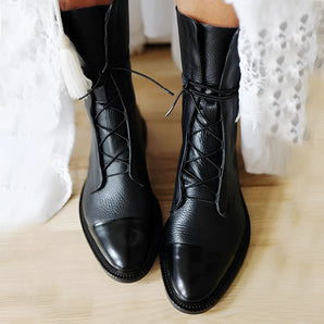 Elegant women's black leather lace-up ankle dress boots being worn, showcasing the sleek design and high-quality leather material.