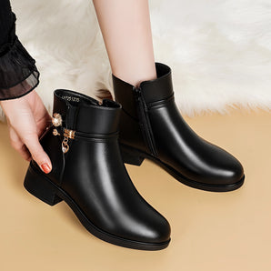 Elegant women's black leather ankle boots showcasing chic winter style, worn on a model's legs with a focus on the fashion design and leather material.