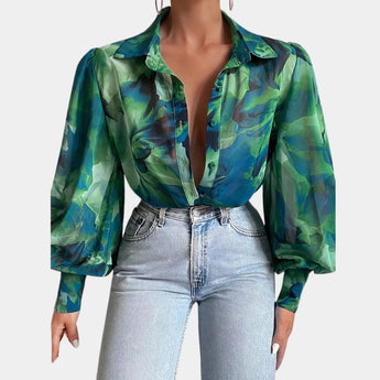
A woman wearing an elegant blue abstract sheer blouse with bell sleeves, designed for an office chic look. The blouse features a loose fit, suitable for professional or casual settings.