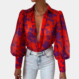 Elegant women's blouse with a blue abstract pattern featuring sheer bell sleeves, a sophisticated collar, and tailored waist, designed for an office chic look.
