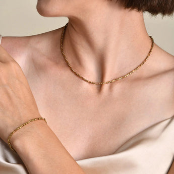 Elegant women's designer gold bracelet worn on wrist, showcasing luxury fine jewelry against a background of a woman's arm and shoulder.
