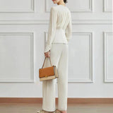 Elegant women's high-waist trouser suit and pleated blouse set displayed on a mannequin, featuring a white blouse with pleated details and a beige high-waist trouser, showcasing shoulder and neck areas with a refined fit.