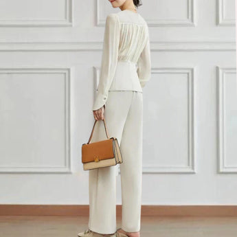 Elegant women's high-waist trouser suit and pleated blouse set displayed on a mannequin, featuring a white blouse with pleated details and a beige high-waist trouser, showcasing shoulder and neck areas with a refined fit.