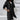 
A stylish black long hooded cardigan designed for women, featuring an asymmetrical zipper, long sleeves, and a flattering fit in size 5XL. The cardigan is worn by a model showcasing fashion-forward outerwear style, complemented by sunglasses.