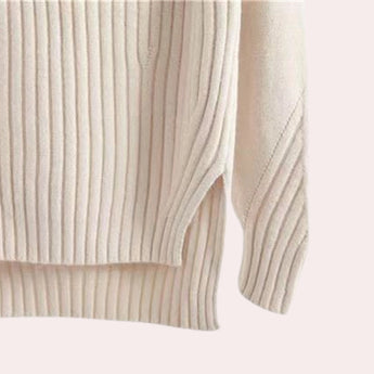 Elegant cream-colored women's ribbed mock neck sweater displayed against a wooden background, showcasing its turtleneck knit design and woolen texture.