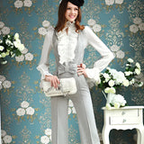 Elegant women's ruffle blouse in white with classic French fashion style, featuring a collar and long sleeves, modeled by a smiling woman with a stylish hairstyle, surrounded by plants and flowers.