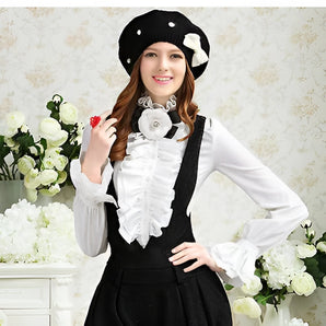 Elegant woman's ruffle blouse in white with cap sleeves and a stylish collar, complemented by a floral accessory and worn with a fashionable hat and gloves. The model is smiling, showcasing classic French fashion style.