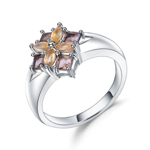 Elegant women's silver ring with multicolor gemstones in a floral design displayed on a woman's finger, showcasing intricate craftsmanship and vibrant colors.