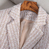 Elegant women's tweed blazer in a chic monochrome design, featuring a structured collar, long sleeves, and a fitted waist, suitable for formal office wear.