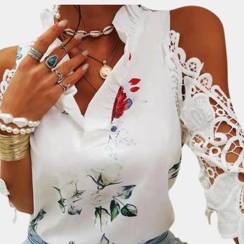 Elegant women's white floral lace cold shoulder bell sleeve top worn by a model, showcasing intricate lace details, shoulder cutouts, and flowing bell sleeves.