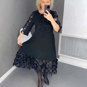 Embellished plus size black high-low dress with polka dot hem, featuring long sleeves and a fitted waist, modeled by a person standing in a stylish pose.