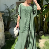 Embroidered green lace maxi dress in a bohemian style, featuring intricate patterns and a flowing design. The dress is presented as formal wear, suitable for summer events, with a focus on the shoulder and waist areas.